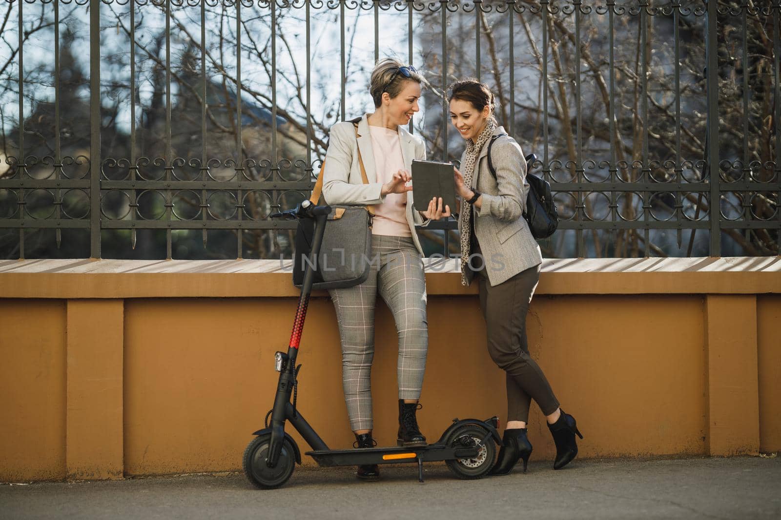 A two successful businesswomen using a digital tablet while having a quick break in the city.