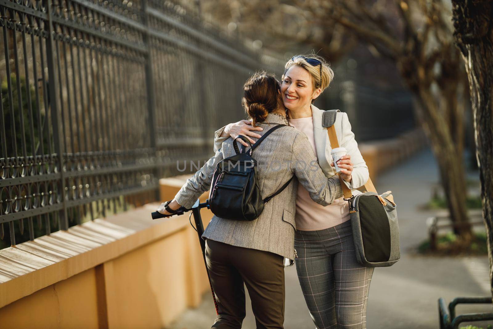 A two successful businesswomen hugging as a greeting while walking through the city.