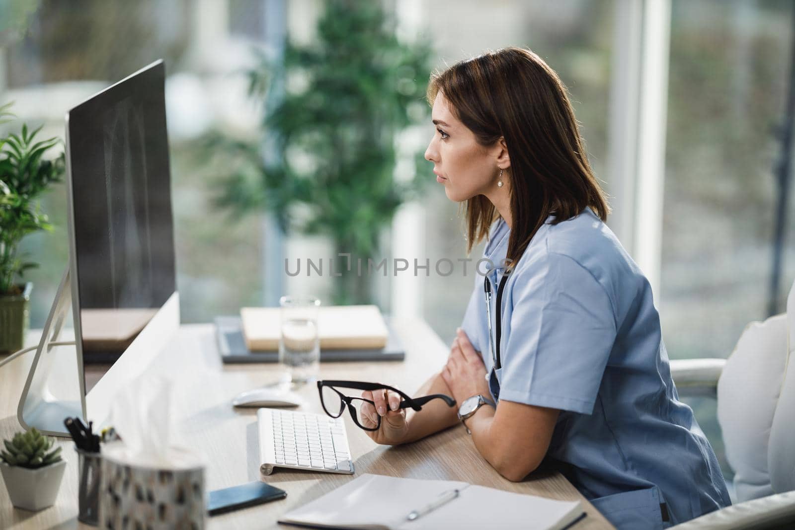 An attractive young female nurse using a computer while sitting at her desk in the hospital.