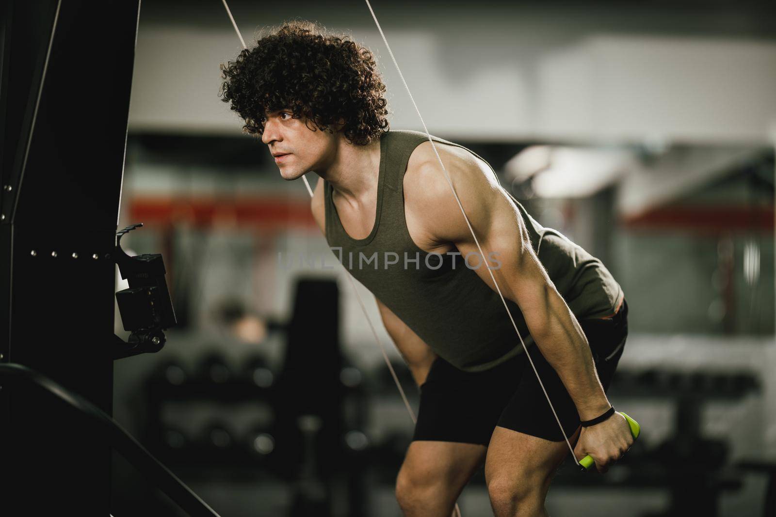 A muscular guy is doing hard ski rope crossfit training in the gym.