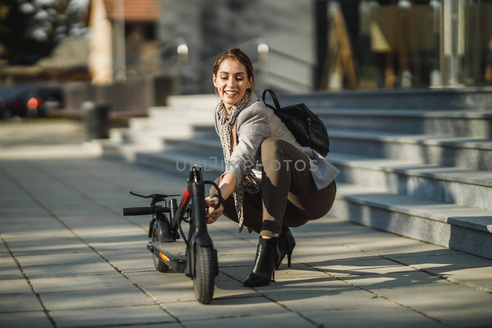 A young businesswoman going to work with an electric push scooter.