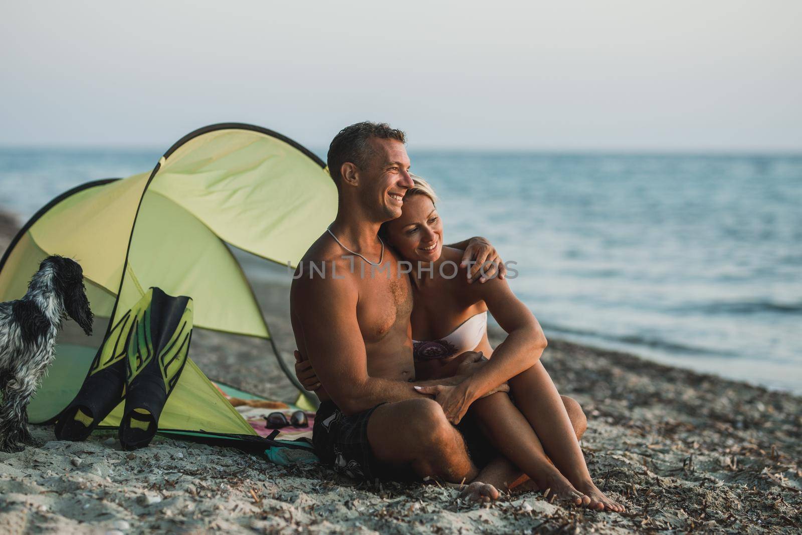 An affectionate happy couple spending day at the beach and enjoying at sunset.