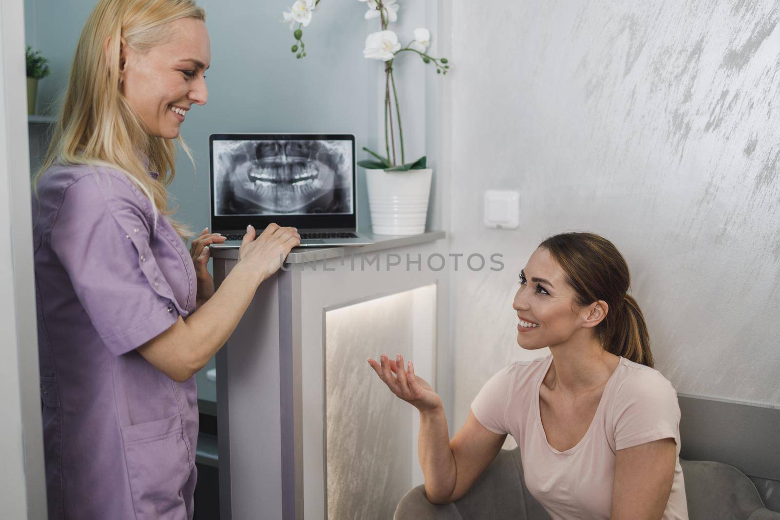 An attractive young woman sitting in waiting room and having a consultation with her dentist.