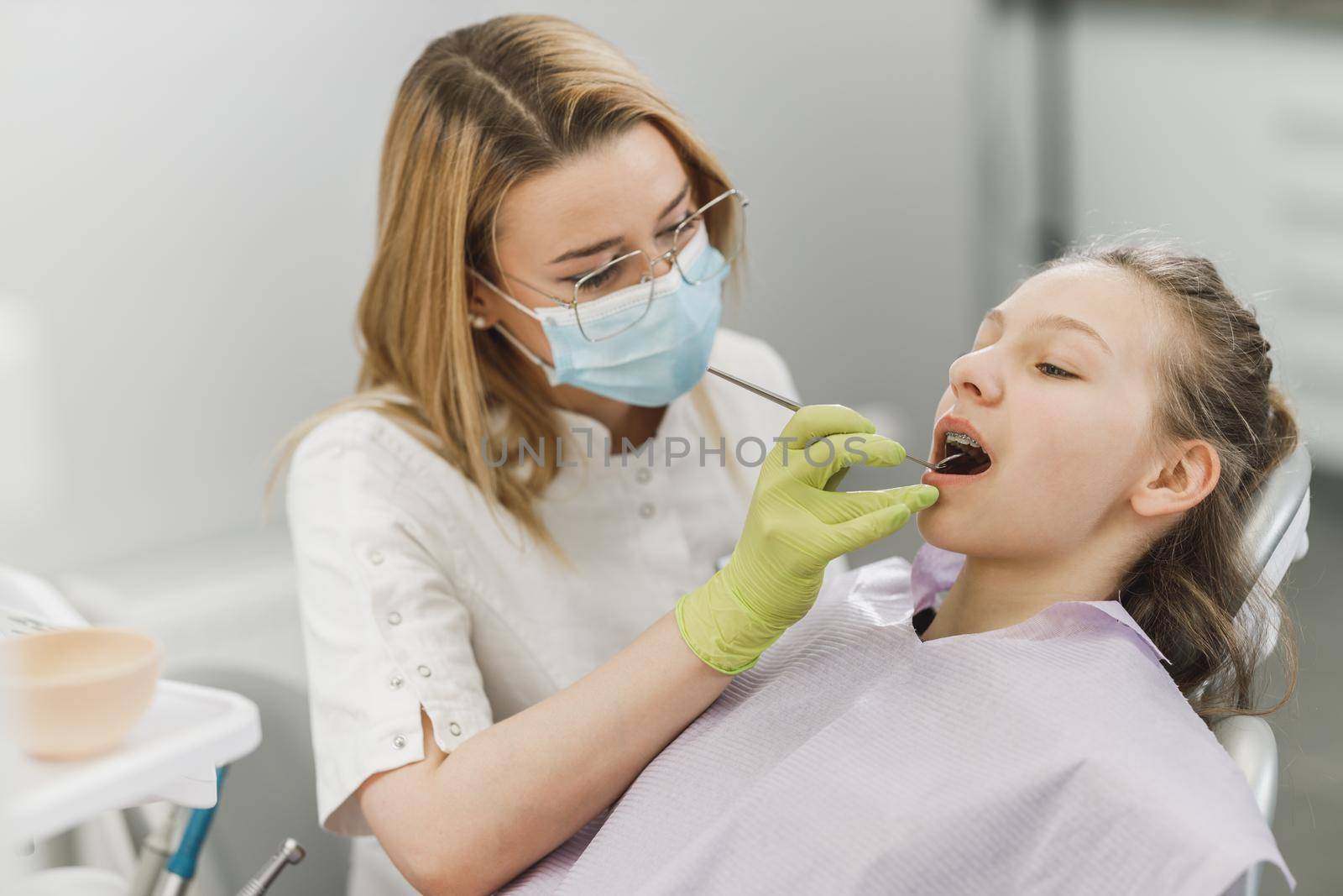 A teenager girl getting her teeth checked by dentist at dental clinic.