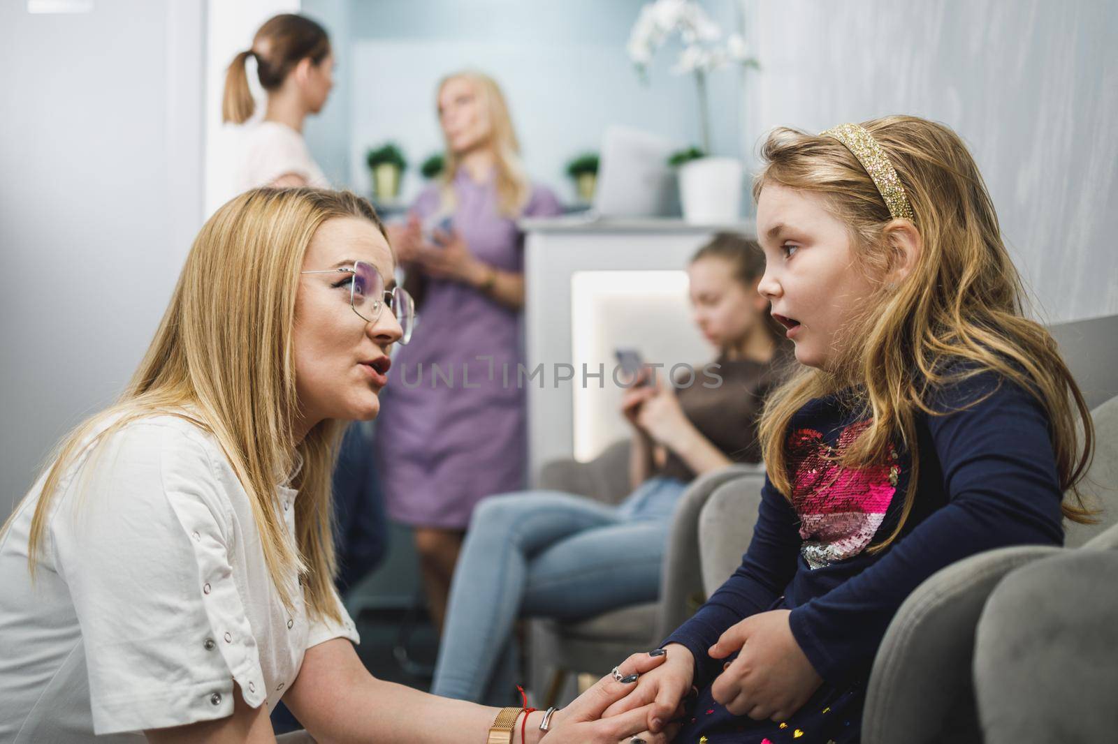 Female dentist and little girl communicating in waiting room at dentist's office.