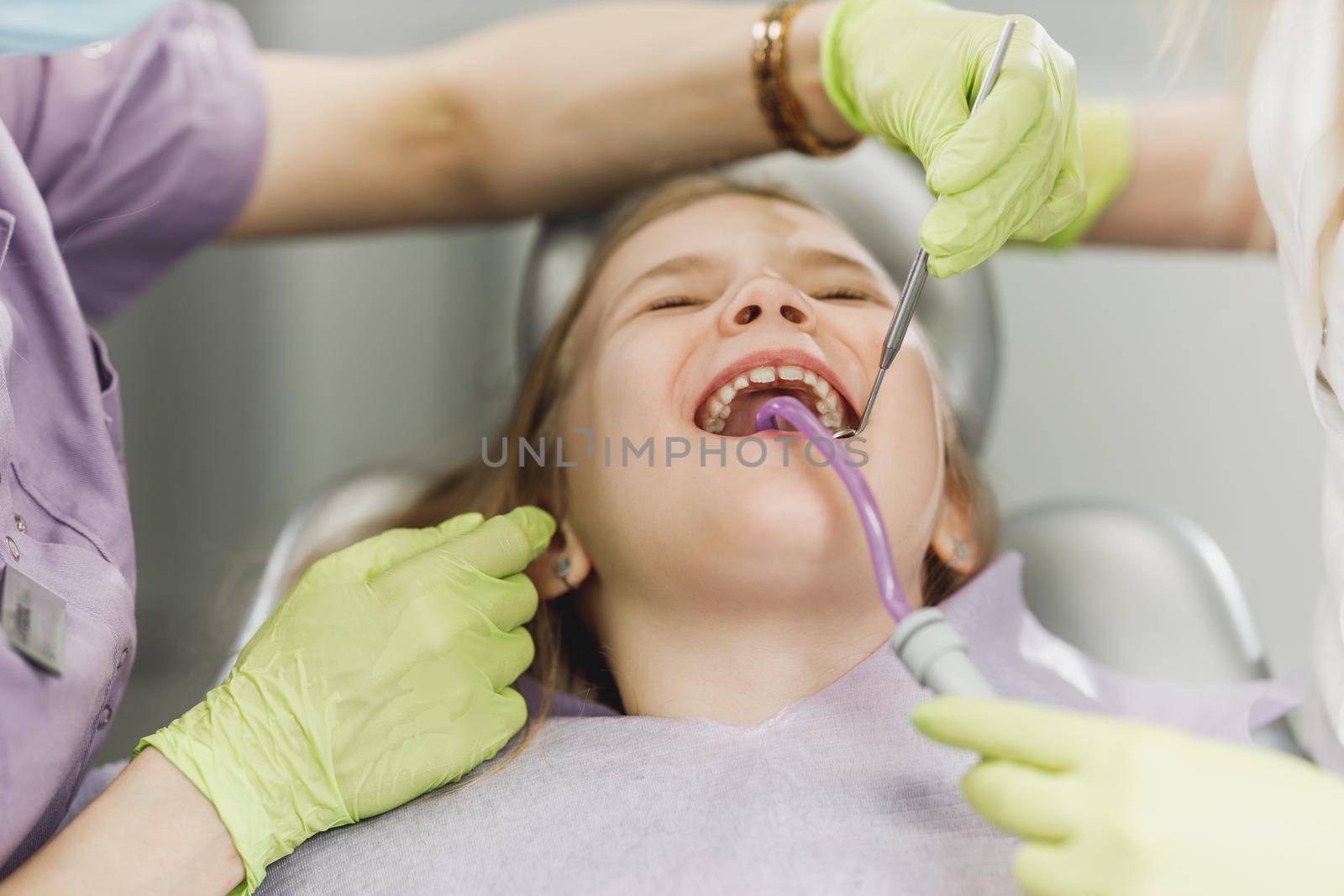 A cute little girl getting her teeth checked by dentist at dental clinic.