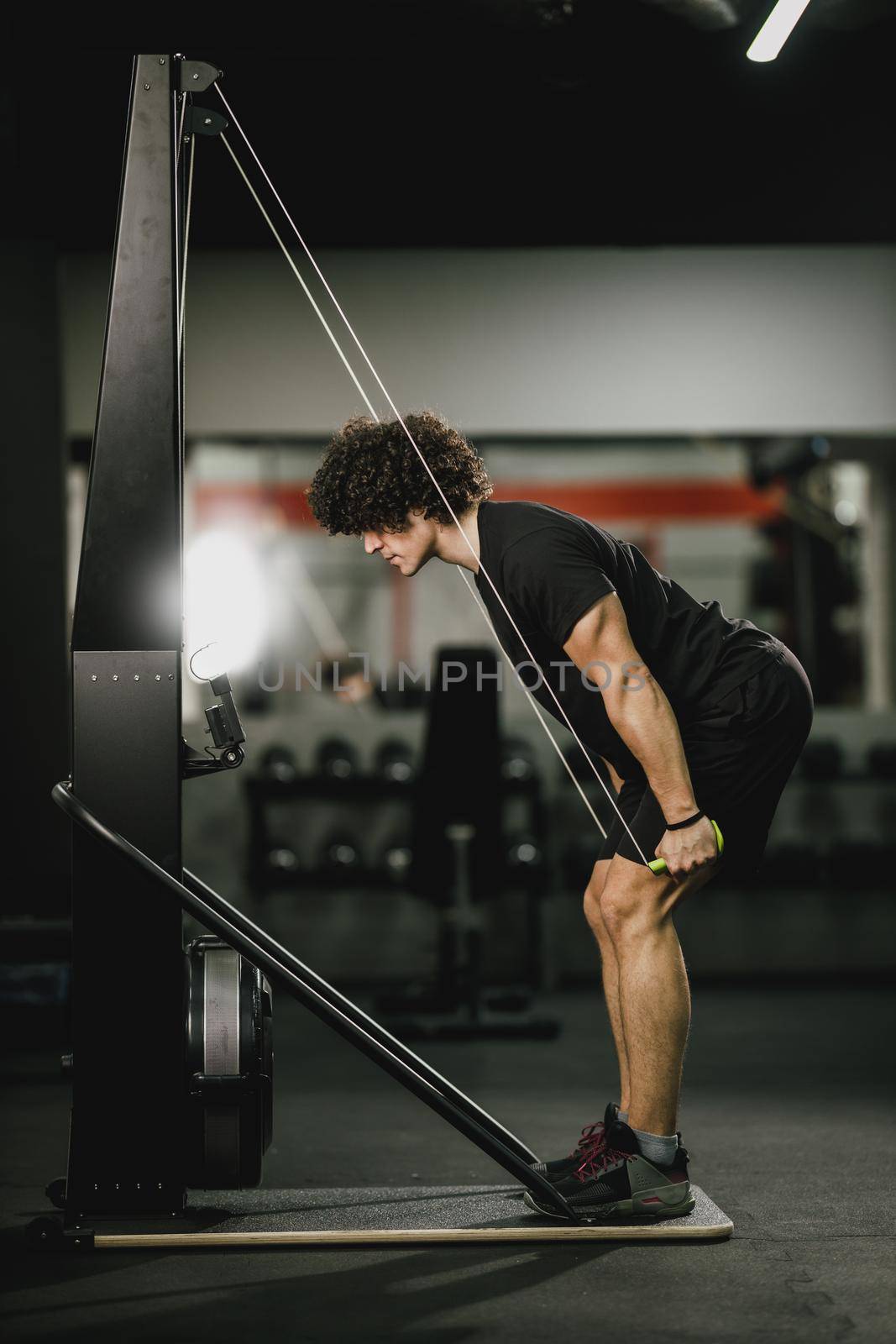 A young muscular man is doing hard ski rope crossfit training in the gym.