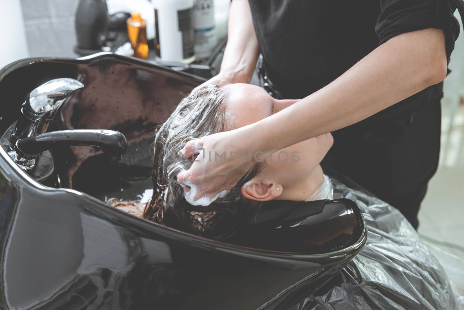 hair stylist washing woman head in hair salon