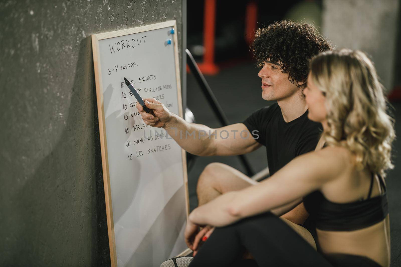 An attractive woman talking about exercise plan with her personal trainer at the gym.