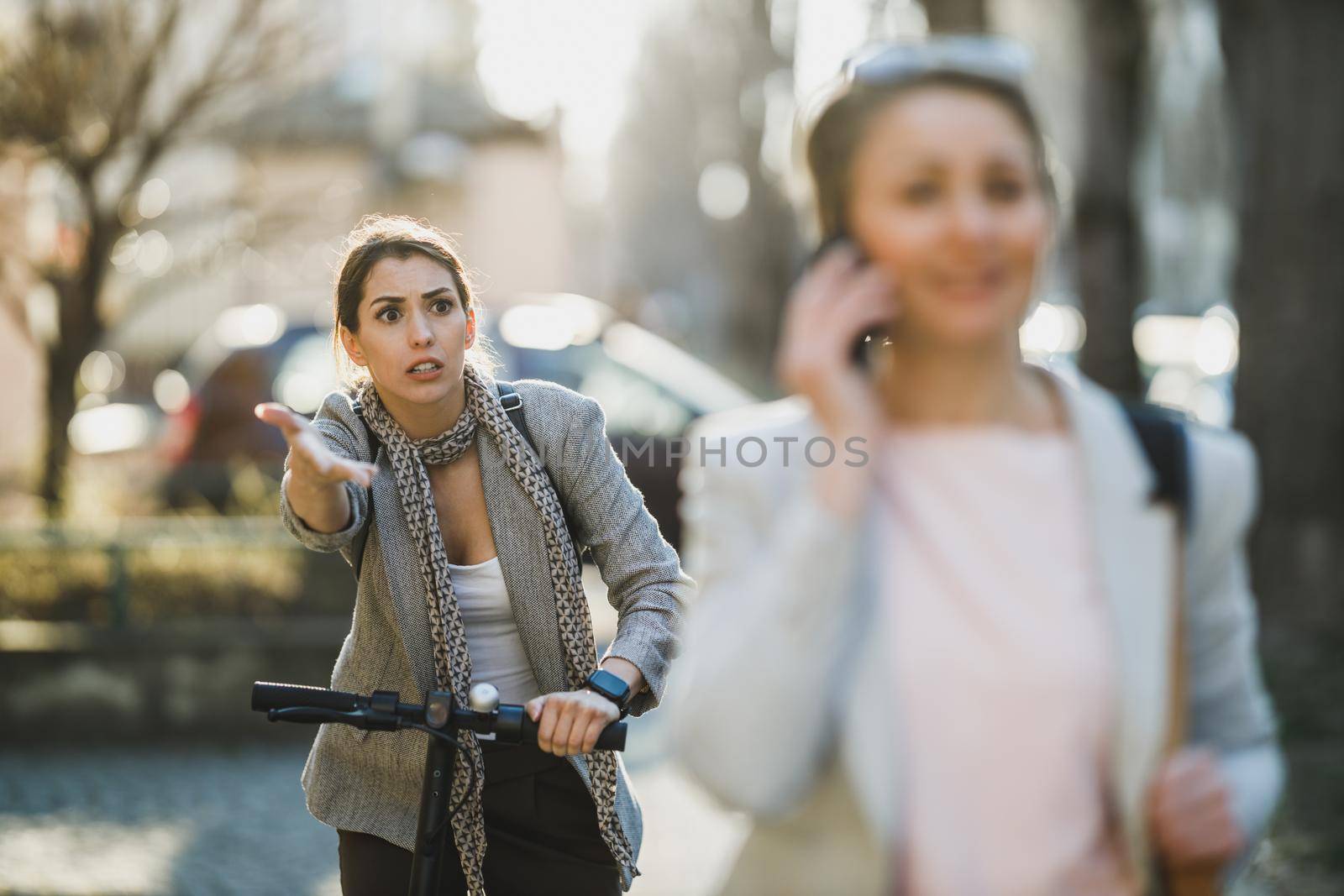Shot of a furious young business woman riding an electric scooter during morning traffic jams.
