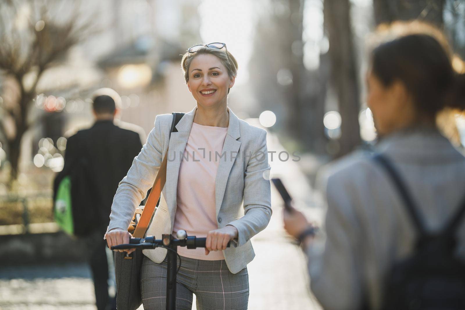 A mature business woman riding an electric scooter on her way to work.