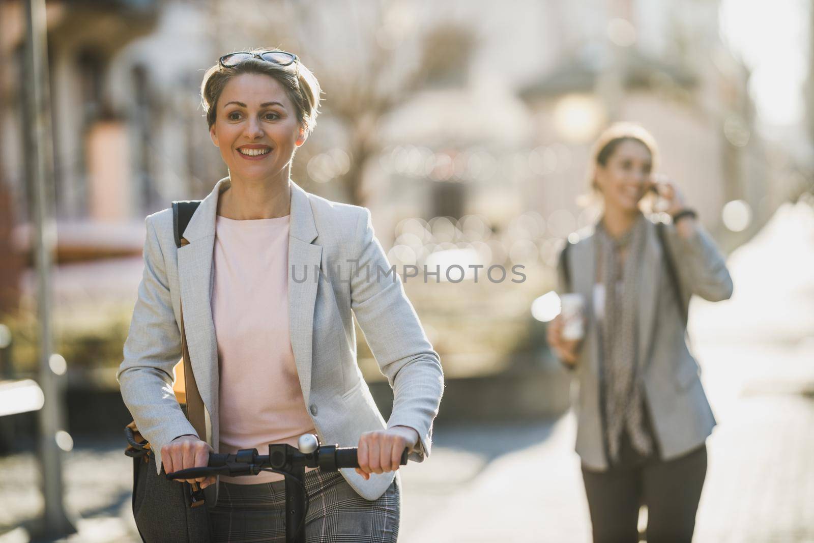 A mature business woman going to work with an electric push scooter.