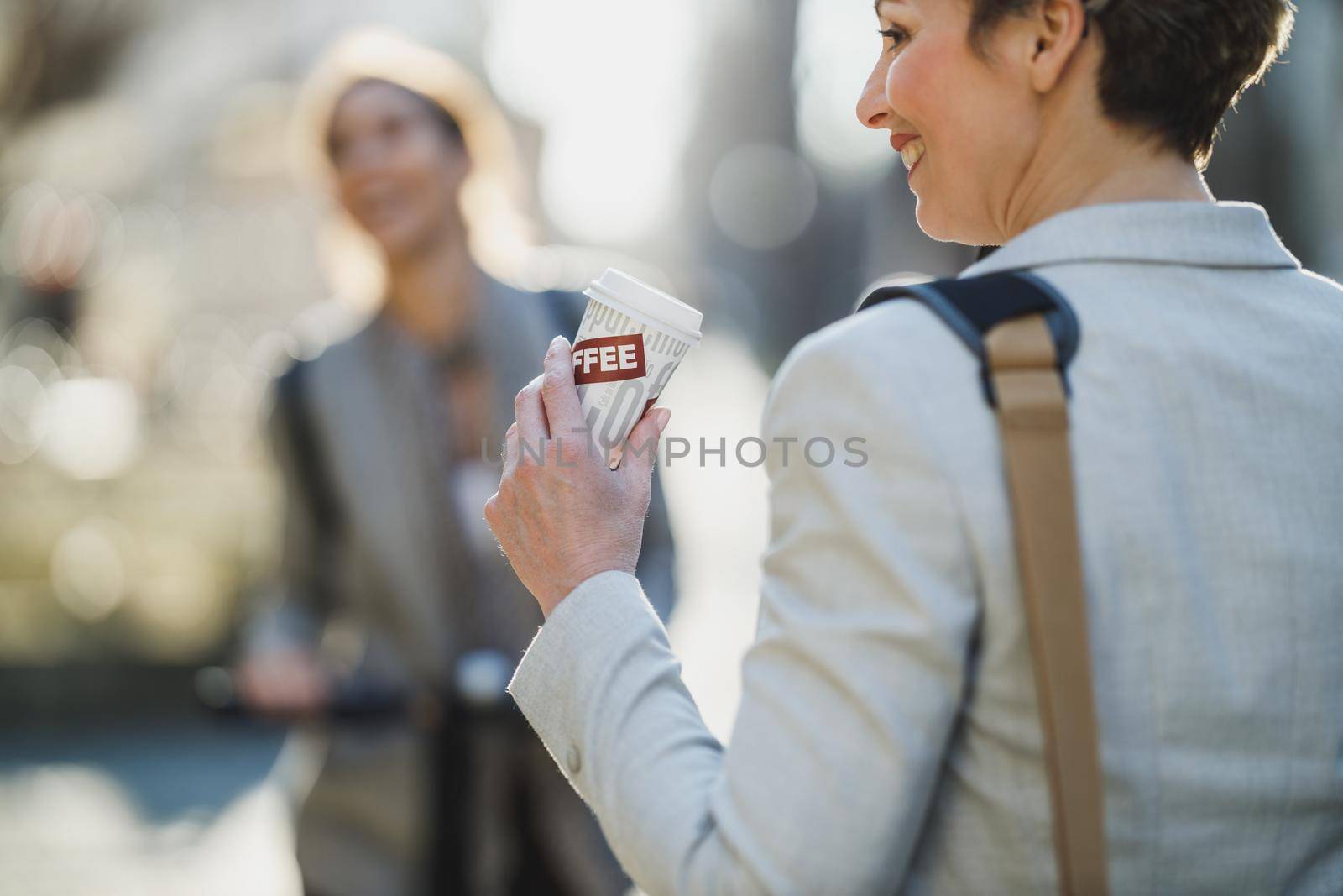 A mature business woman drinking coffee while go to work through the city.