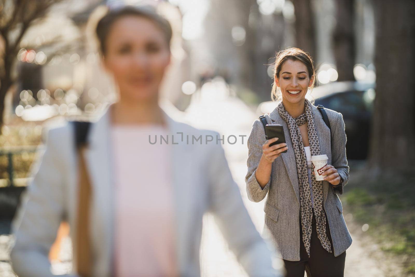 A young business woman typing on a her smart phone during quick coffe break.