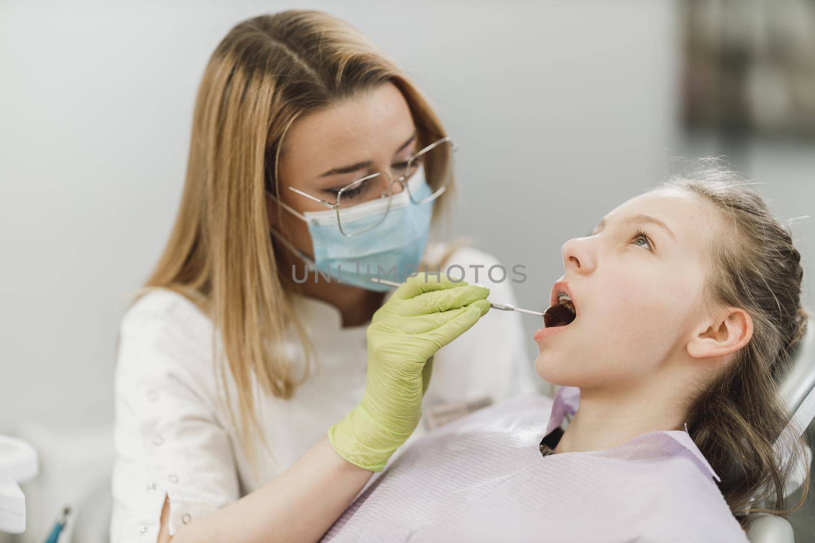 A teenager girl getting her teeth checked by dentist at dental clinic.