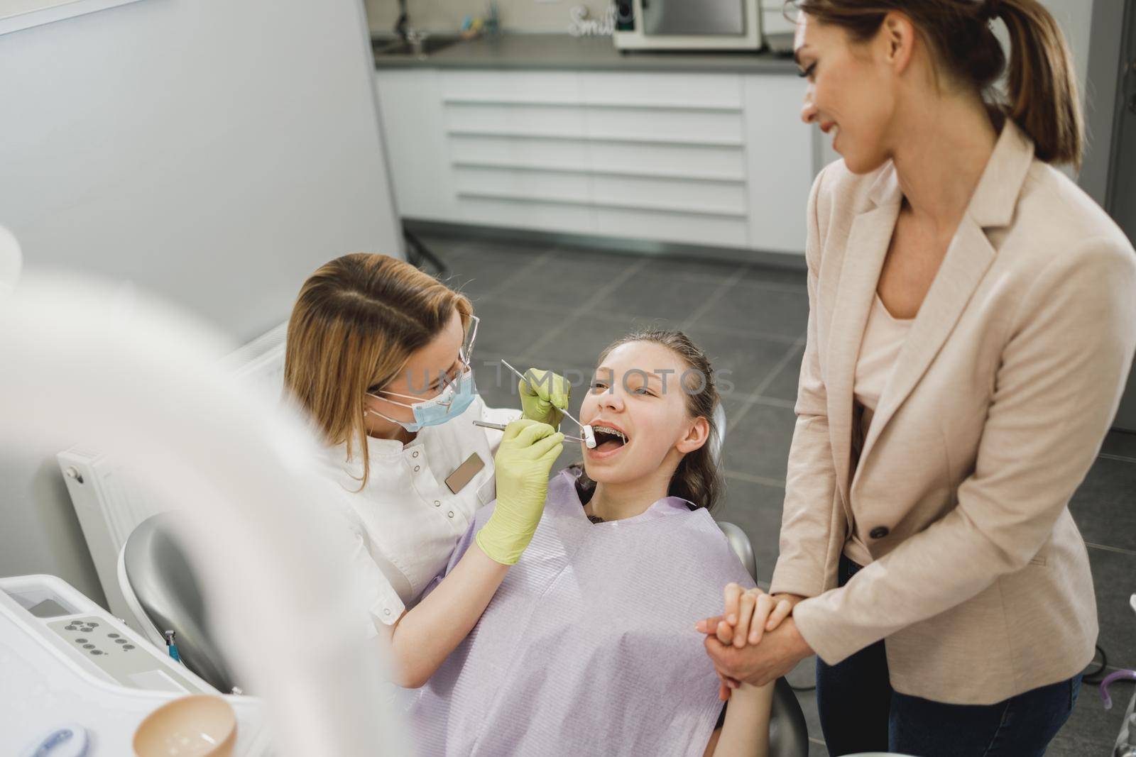 A teenager girl with her mom getting her teeth checked by dentist at dental clinic.