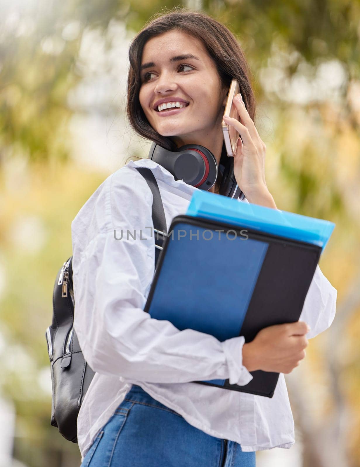 Student, woman and phone call at campus, outdoor and smile for conversation, chat and excited in summer. Young gen z girl, smartphone communication and networking at university with books in sunshine by YuriArcurs