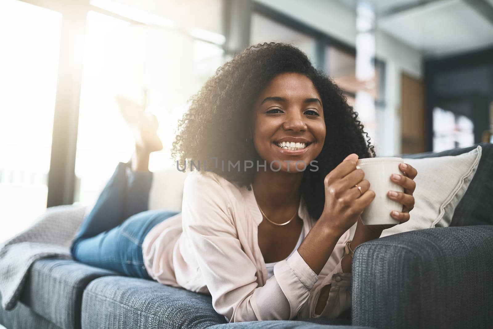 Coffee keeps me smiling. an attractive young woman relaxing at home. by YuriArcurs