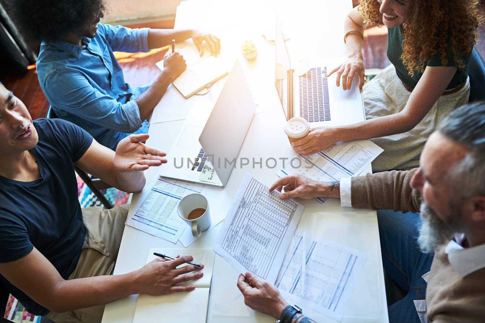 Keeping success in their forecasts. High angle shot of a group of businesspeople going through paperwork in an office. by YuriArcurs
