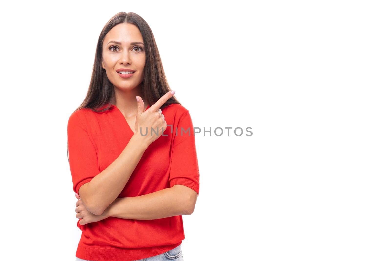 young cute caucasian brunette in a red short-sleeved shirt points with index fingers at the space for advertising.