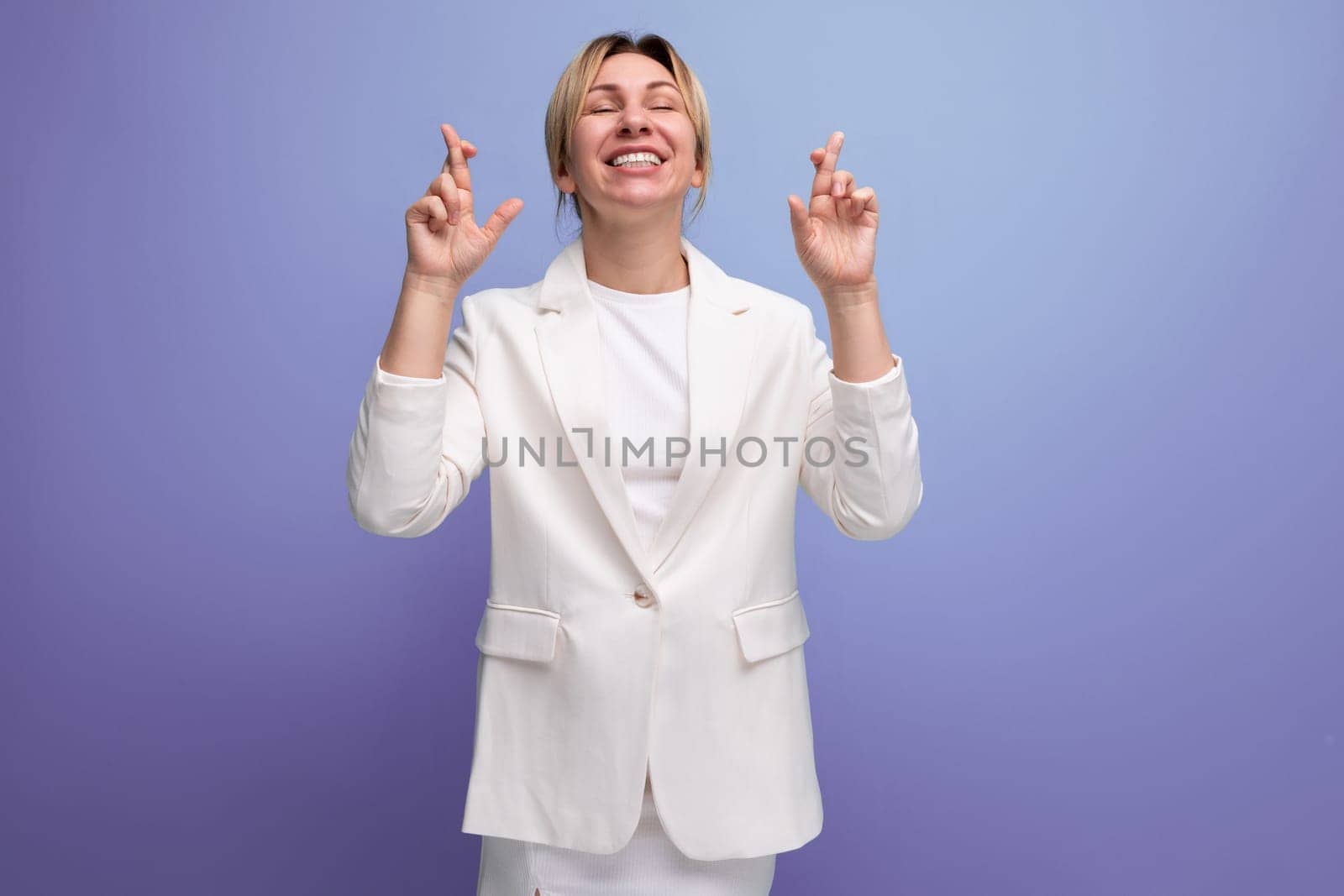 adorable kind young blond business leader woman dressed in a white jacket and skirt dreamily looks up.