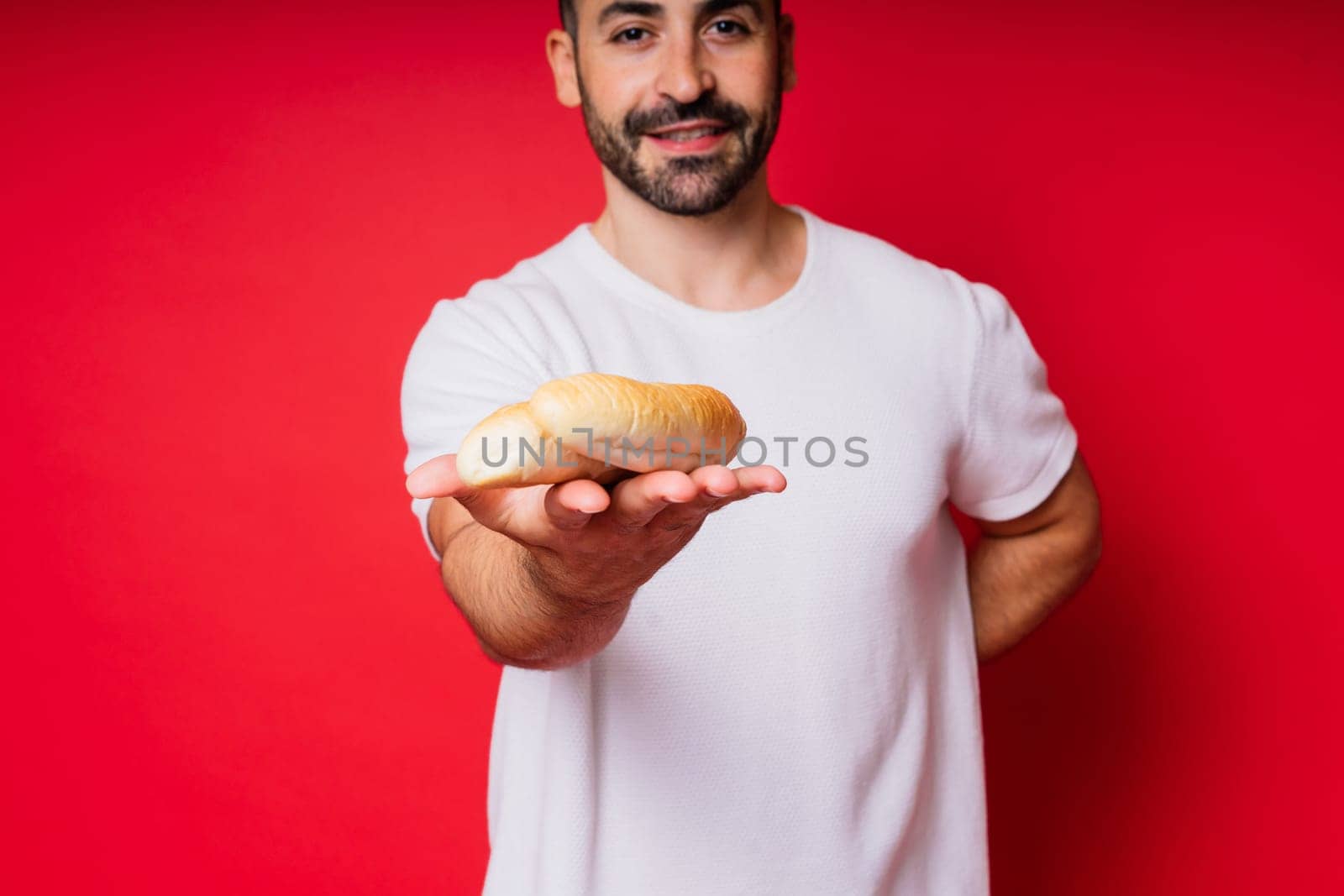 Man with freshly baked bread in the hands isolated on red background studio by Zelenin