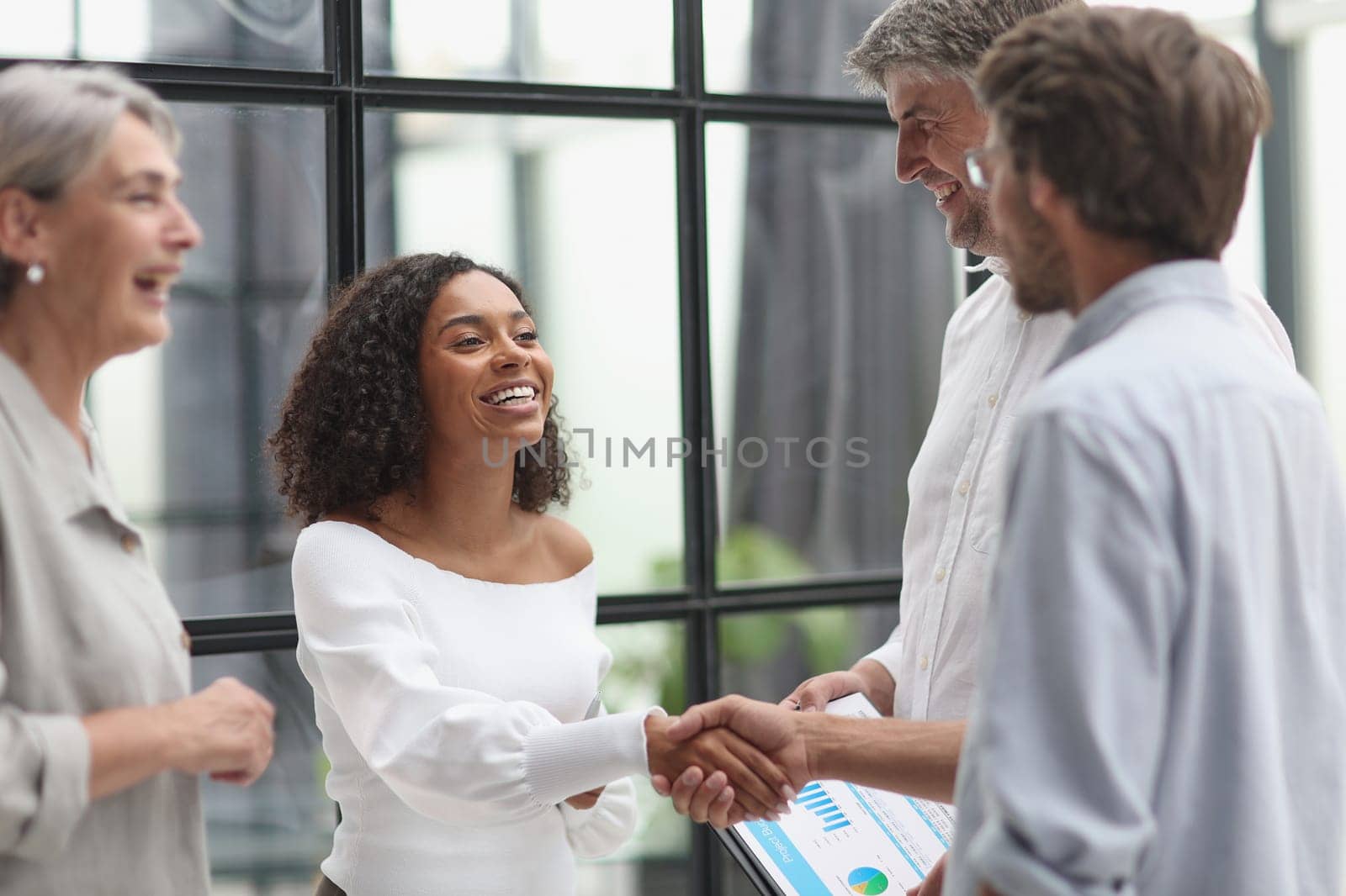 Smiling multiethnic businesspeople shaking hand in office.