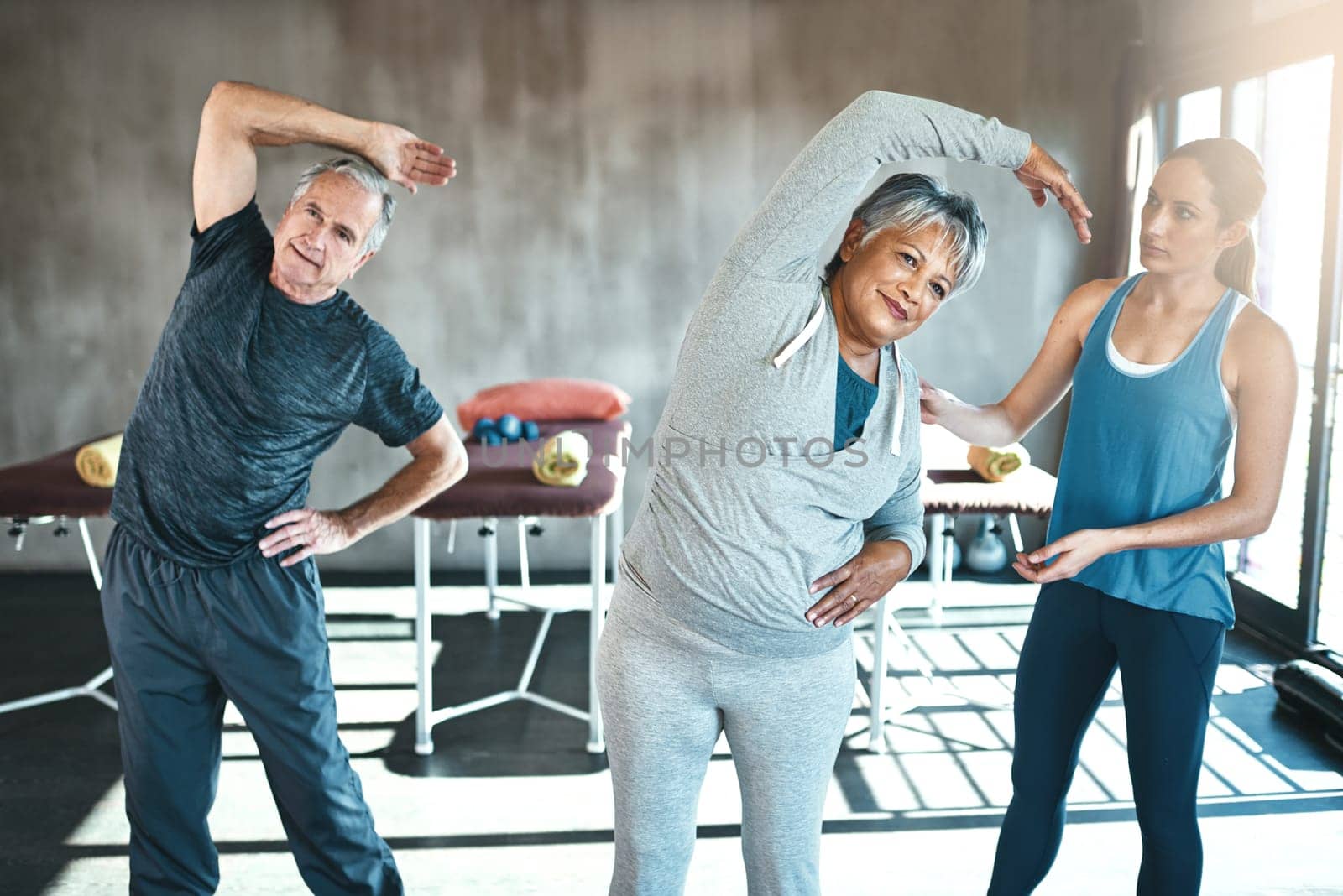 Stretching, help and old couple with personal trainer for fitness, wellness and physiotherapy. Health, workout or retirement with senior patient and physiotherapist in gym for warm up training by YuriArcurs