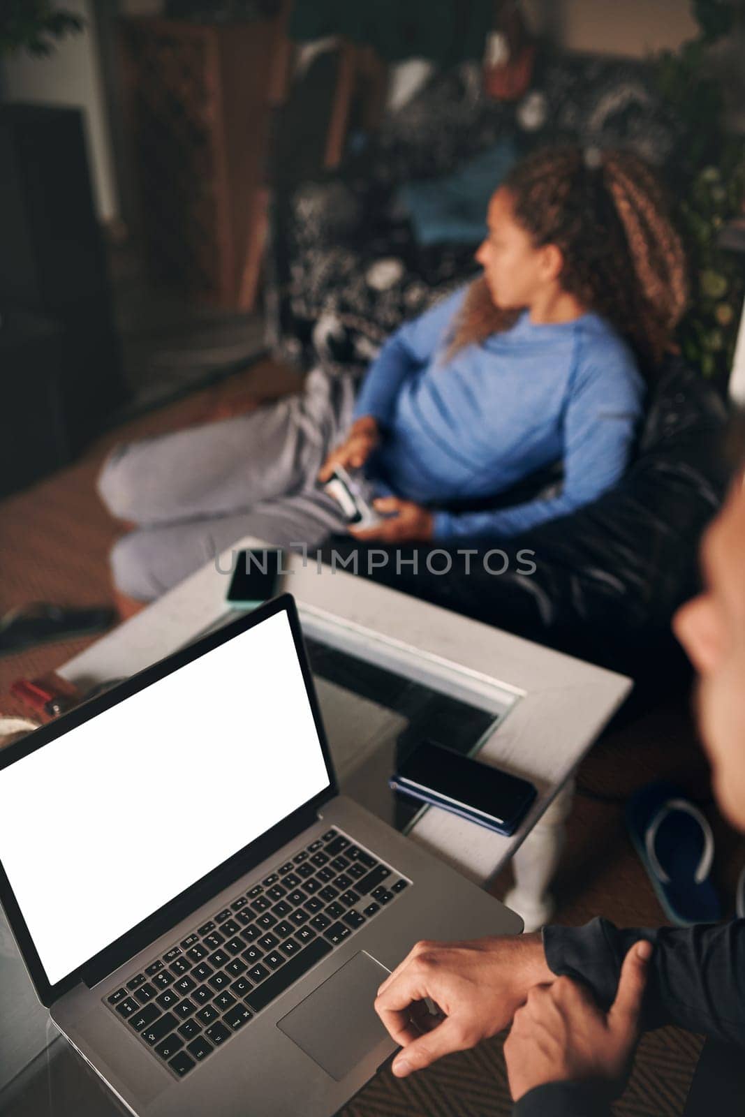 Theres a time for business and a time for pleasure. a young woman playing video games while her boyfriend uses a laptop at home