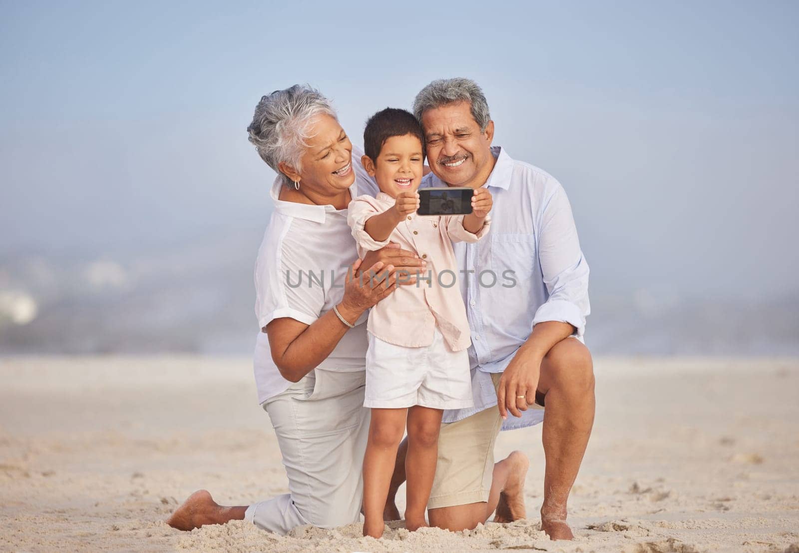 Selfie, travel and grandparents with child at beach for vacation, bonding and generations. Picture, happy and young boy with senior man and woman in nature for smile, happiness and technology by YuriArcurs
