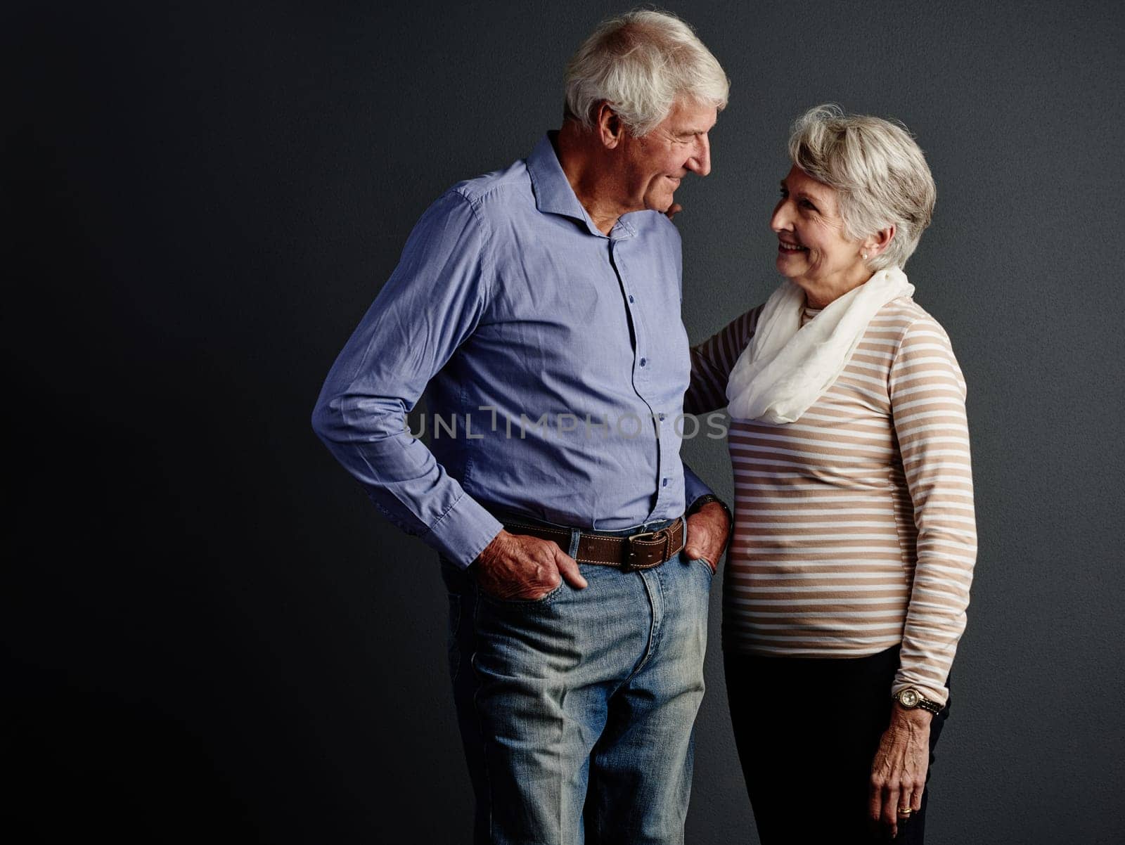 Gazing deeply into her eyes. Studio shot of an affectionate senior couple posing against a grey background