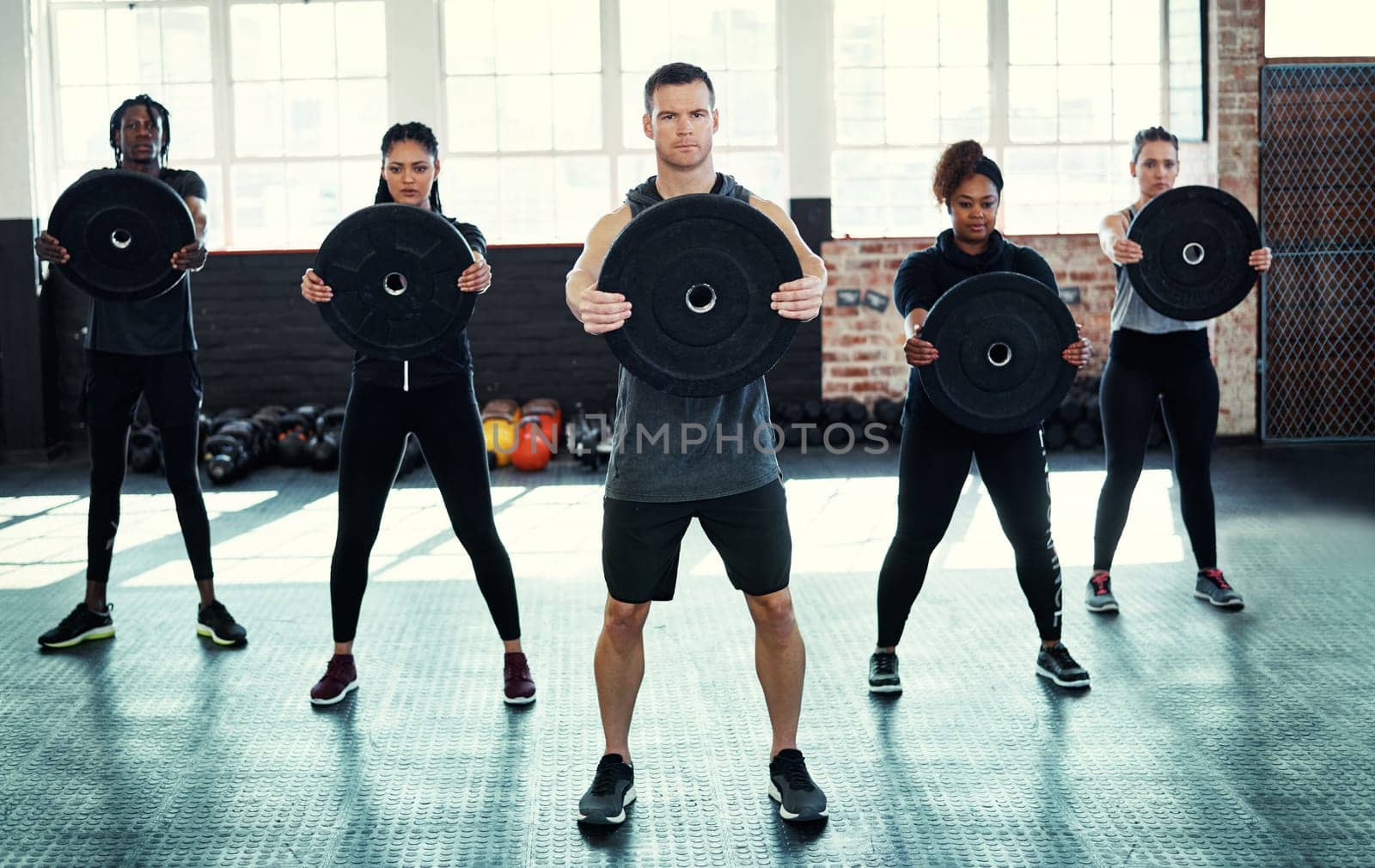 Your effort makes all the difference. a fitness group using kettle-bells in their session at the gym. by YuriArcurs