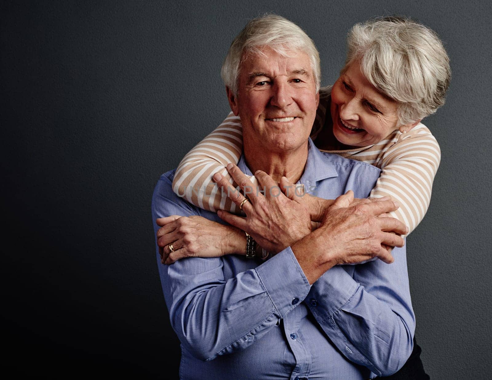 Its a match made in heaven. Studio portrait of an affectionate senior couple posing against a grey background. by YuriArcurs
