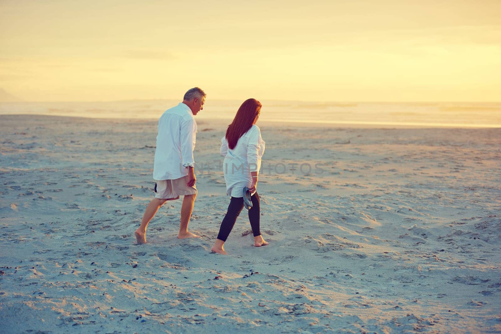 Strolls on the beach...no words needed. a mature couple going for a relaxing walk on the beach. by YuriArcurs