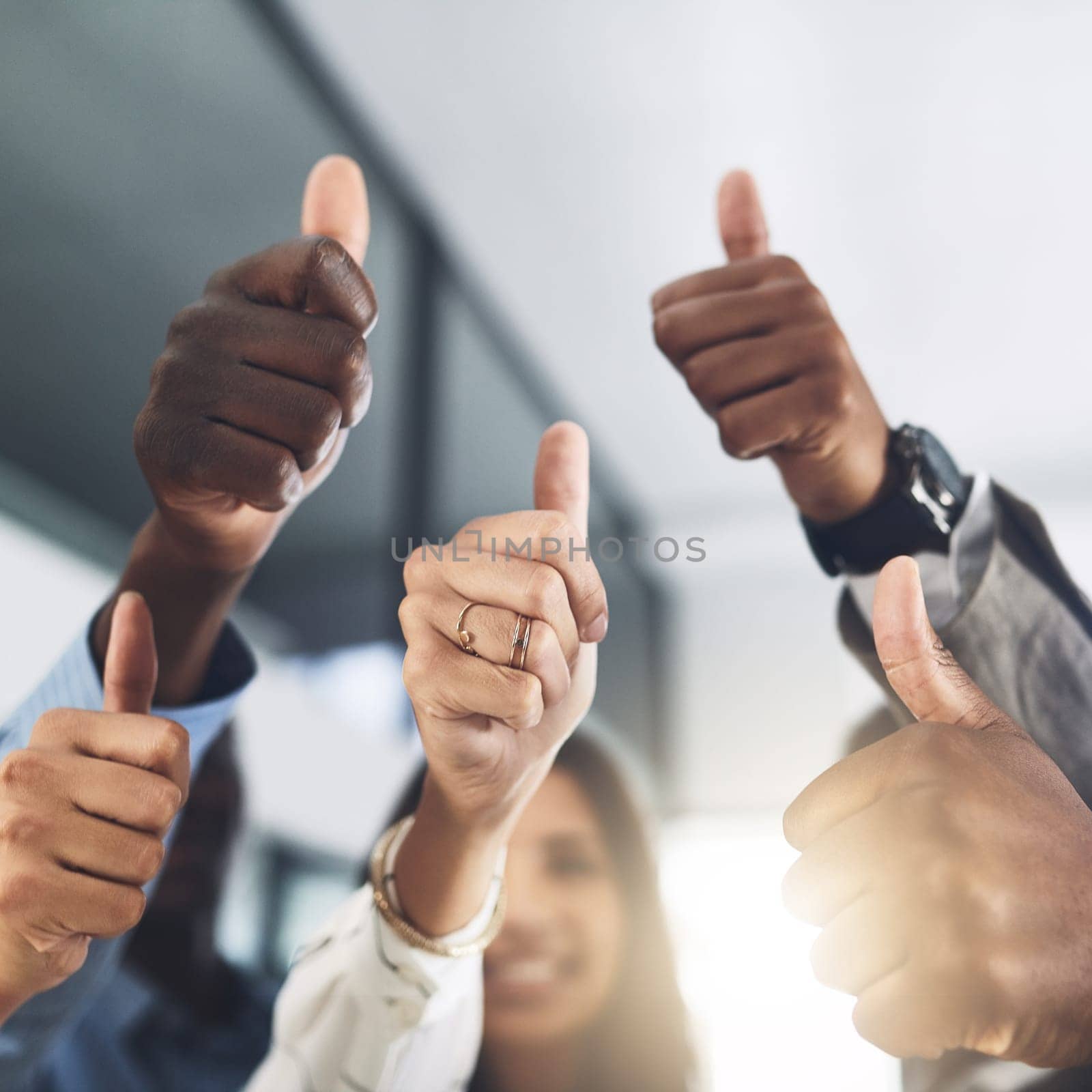 Its a big YES from us. Closeup shot of a group of businesspeople showing thumbs up in an office. by YuriArcurs