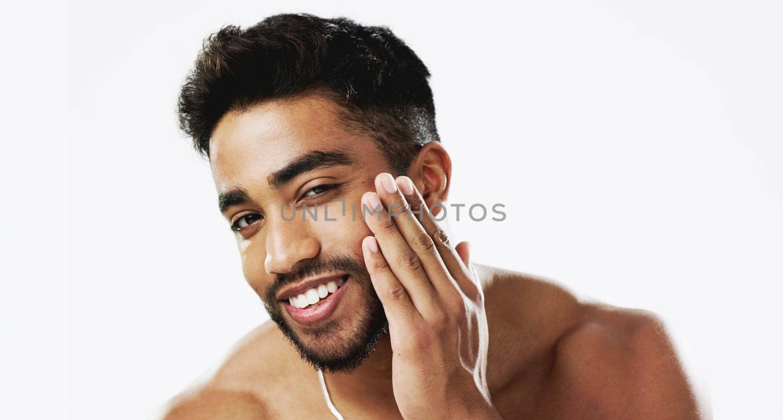 Skincare, man and hands of face, happy and laughing against white background space. Touch, smile and portrait of Indian male model excited for wellness, beauty and cosmetic care result while isolated.