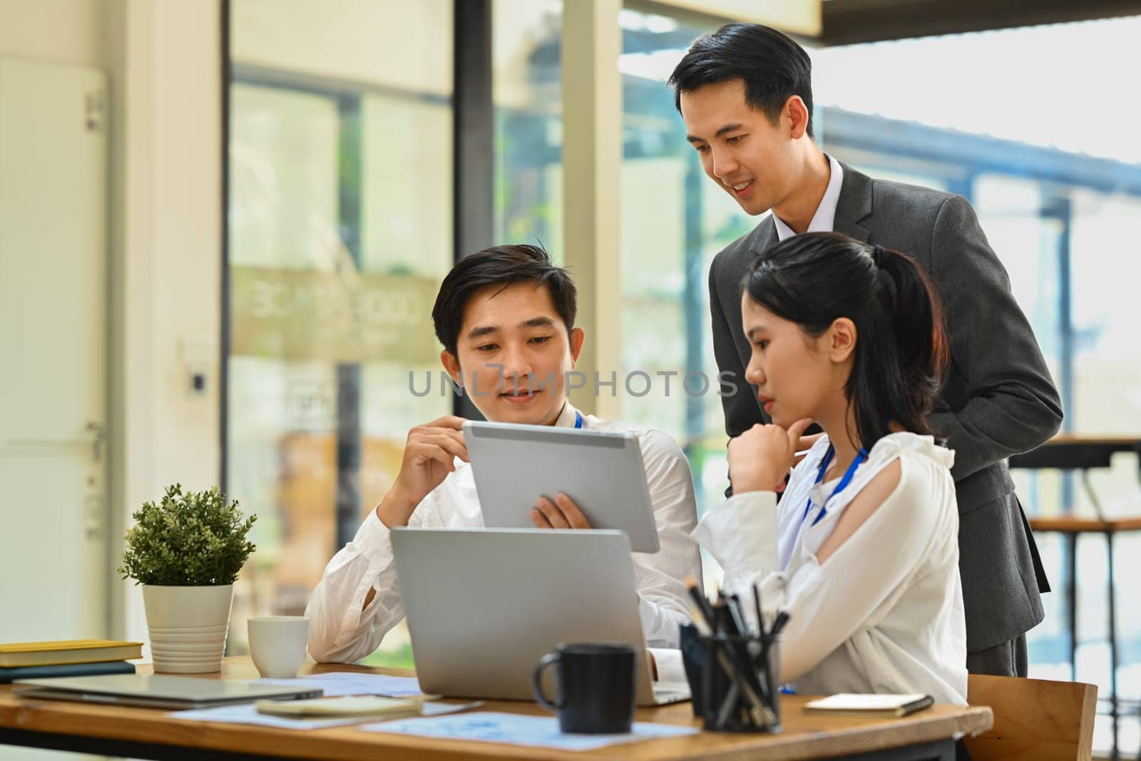 Group of businesspeople analyzing sales statistics data on digital tablet together using meeting in office.