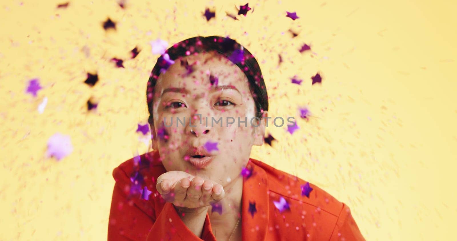 Studio, asian woman blowing confetti and celebration for birthday, anniversary or celebrating Chinese new year. Happy party, smile and model from china on yellow background to celebrate with glitter.
