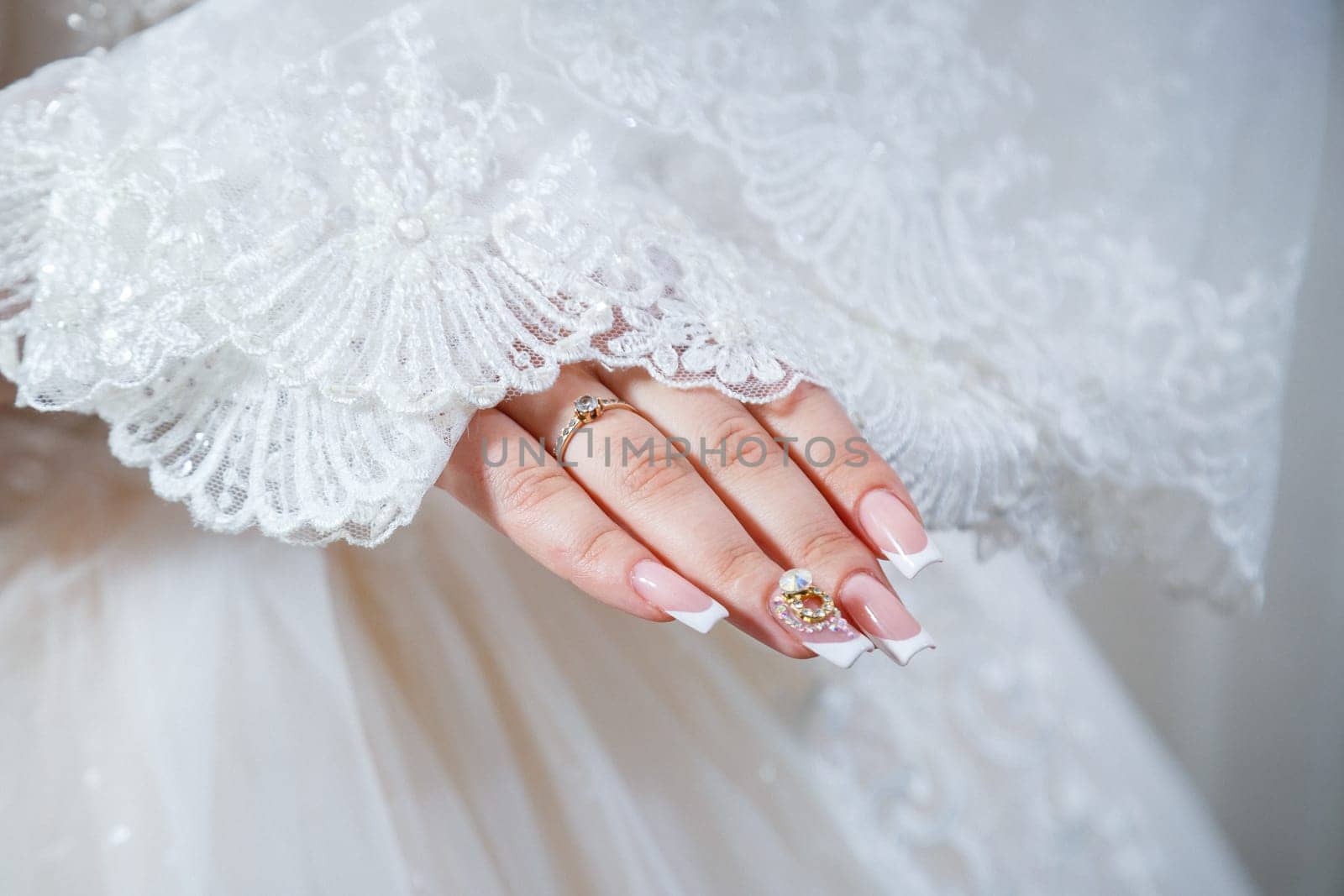 Bride's hands folded on a white wedding dress