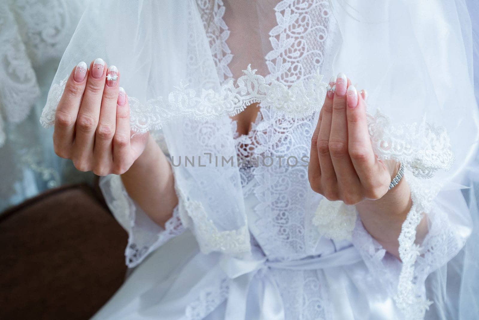 Bride's hands folded on a white wedding dress