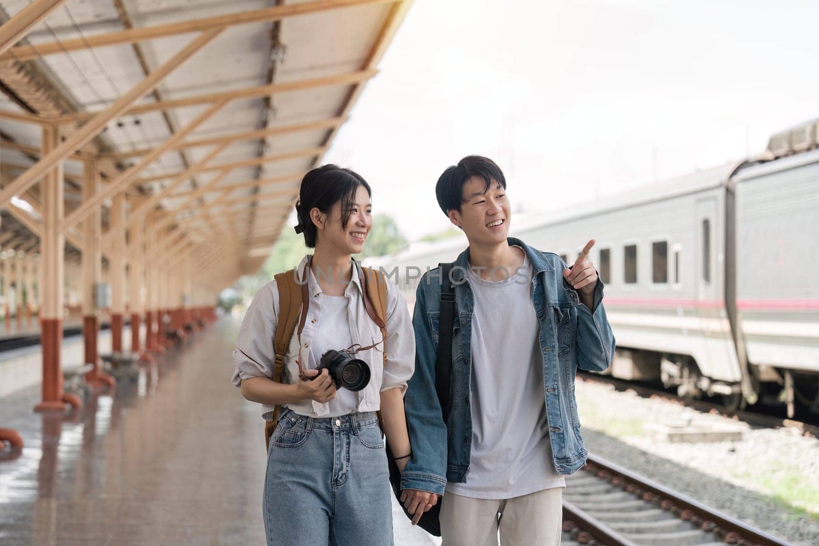 Beautiful couple at railway station waiting for the train. Young woman and man waiting to board a train by nateemee