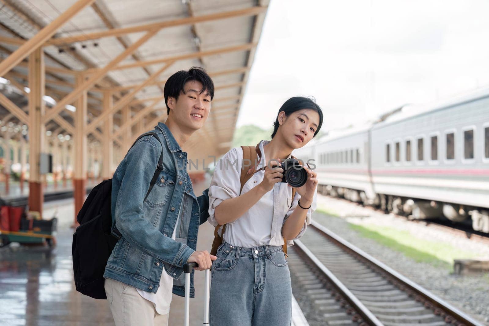 Beautiful couple at railway station waiting for the train. Young woman take pictures of trains. woman and man waiting to board a train.