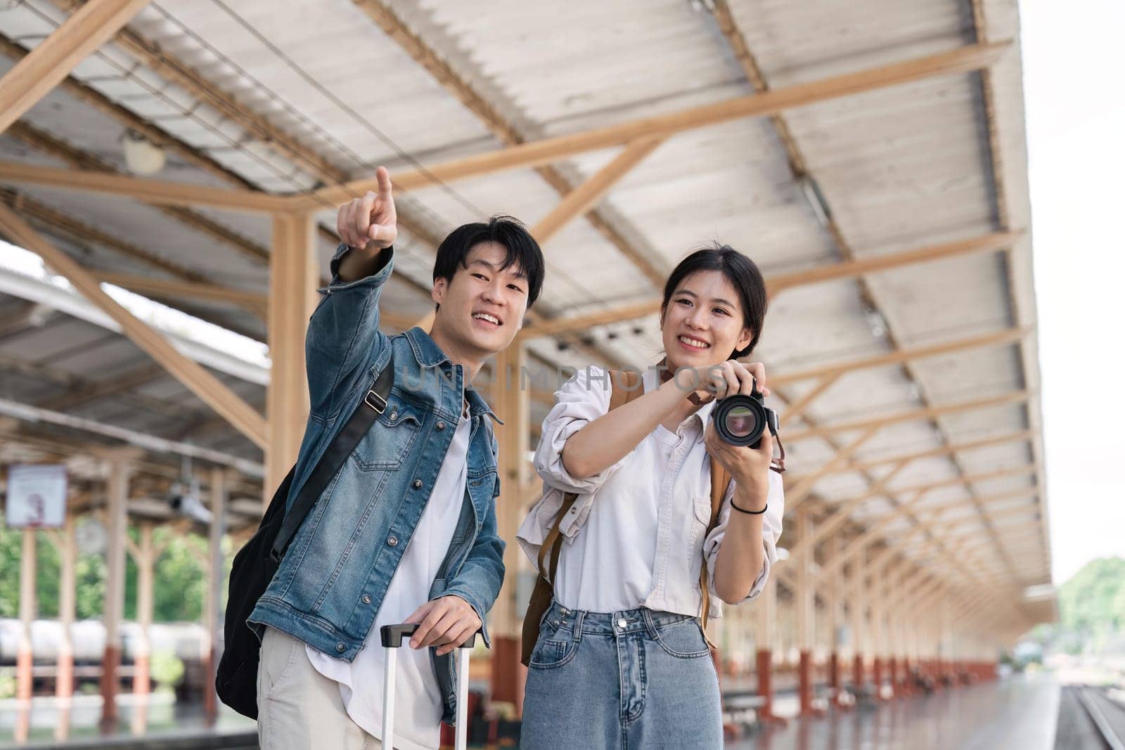 Beautiful couple at railway station waiting for the train. Young woman take pictures of trains. woman and man waiting to board a train.