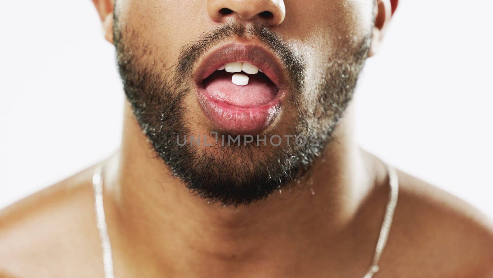 Man, mouth and hands with pill, drug or medication for relief, healthcare or substance abuse against a white studio background. Lips and tongue of male addict taking medical supplement vitamin tablet.