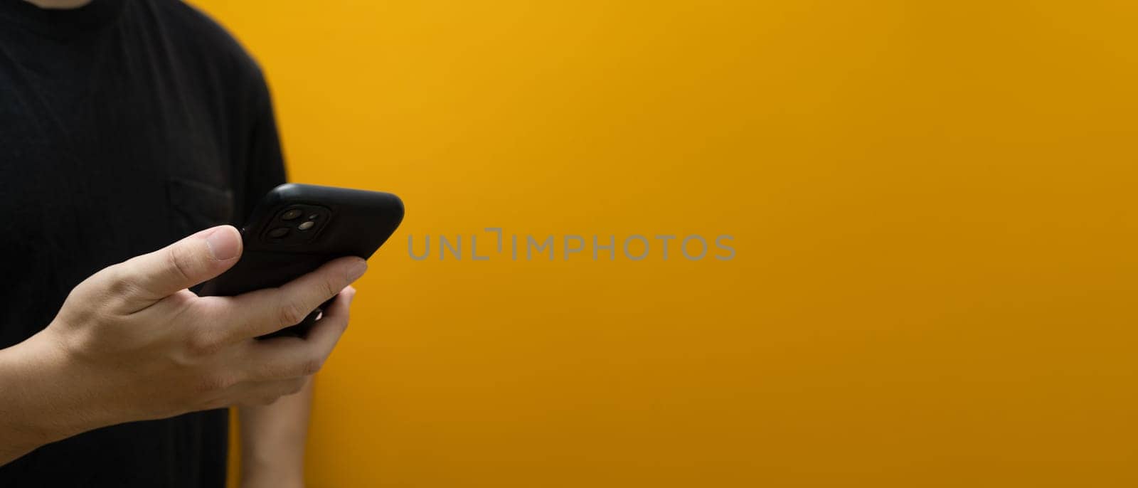 Man hand holding smartphone isolated on yellow background with copy space for advertise text.