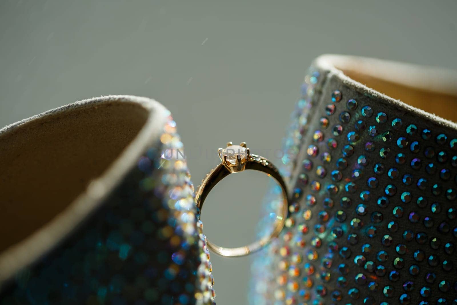 Gold ring of the bride with a pebble between white shoes with heels. Bride's precious ring