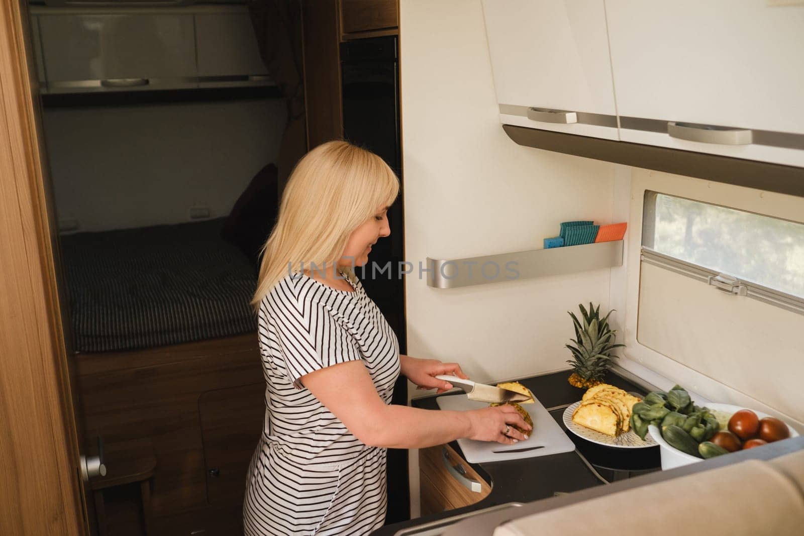 a woman cooking food in the kitchen inside a motorhome, the interior of a motorhome.