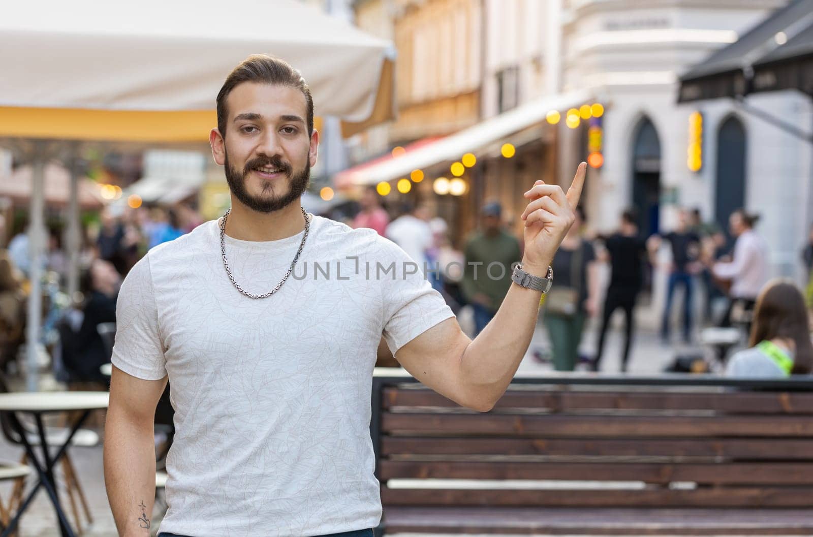 Thoughtful young man showing pointing empty place advertising area for commercial text copy-space for goods promotion. Guy tourist pondering a solution, inspiration dreaming outdoors in city street