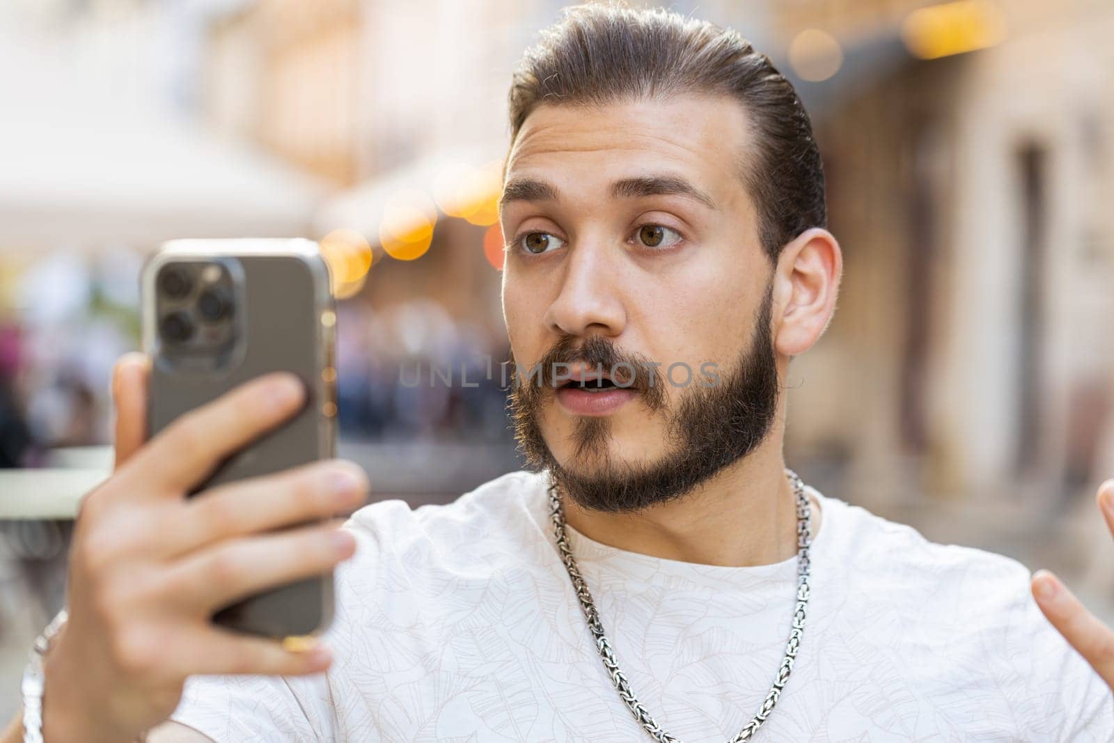 Oh my God Wow. Excited happy joyful winner bearded young man use smartphone typing browsing celebrating win good message news. Guy with mobile phone walking in urban sunshine city street outdoors