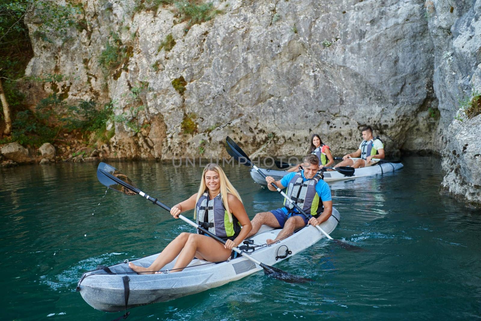 A group of friends enjoying having fun and kayaking while exploring the calm river, surrounding forest and large natural river canyons.